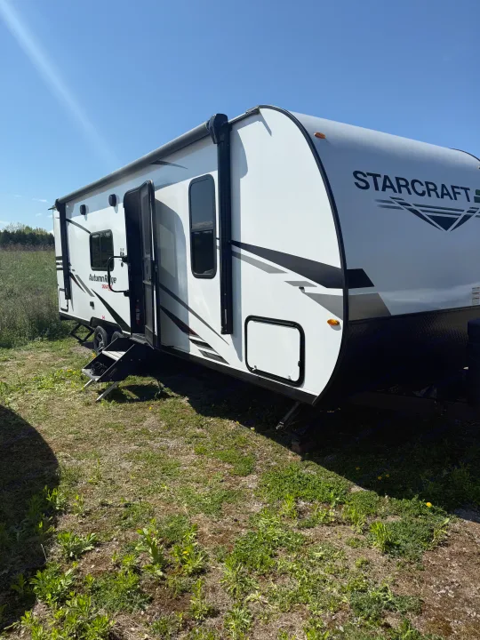 This white Starcraft travel trailer, perfect for an RV rental, is parked outdoors with steps down on a sunny day.. Starcraft Autumn Ridge 2023