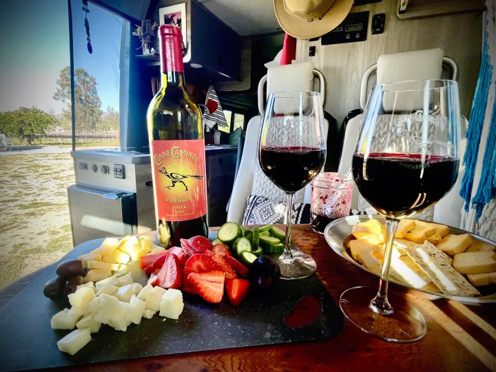 Relaxing in an RV rental with red wine, a charcuterie board featuring cheese, fruit, veggies, and crackers, enjoying the view.. Dodge Winnebago 2021