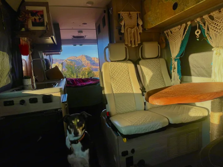Cozy RV rental interior: a dog, swivel seats, table, kitchen, and a stunning mountain view from the rear doors.. Dodge Winnebago 2021