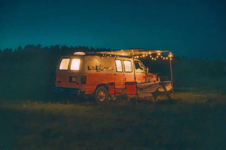 Cozy RV rental at night with string lights illuminating a picnic setup for a relaxing camping adventure.. Ford Econoline E250supercab 2012