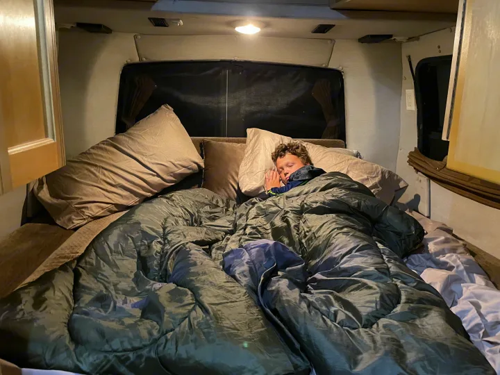 Boy peacefully sleeping in a cozy bed inside an RV rental. Ideal for family road trips & comfort.. Roadtrek 210 - Popular 2005