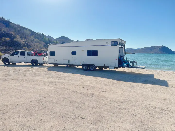RV rental toy hauler parked beachside, truck attached, with a deck over the water. Desert mountains in the background.. Thor Motor Coach Tahoe 2003