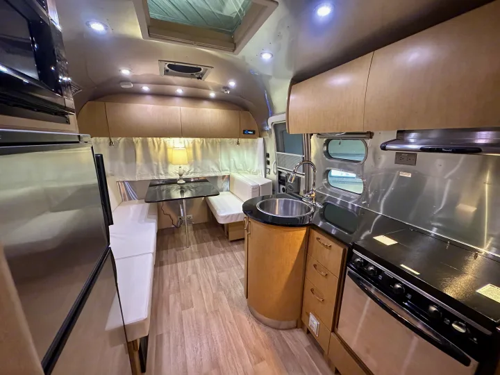 Looking into a bright, modern rv rental interior with a fully equipped kitchen on the right and a comfortable dinette.. Airstream Flying Cloud 2012