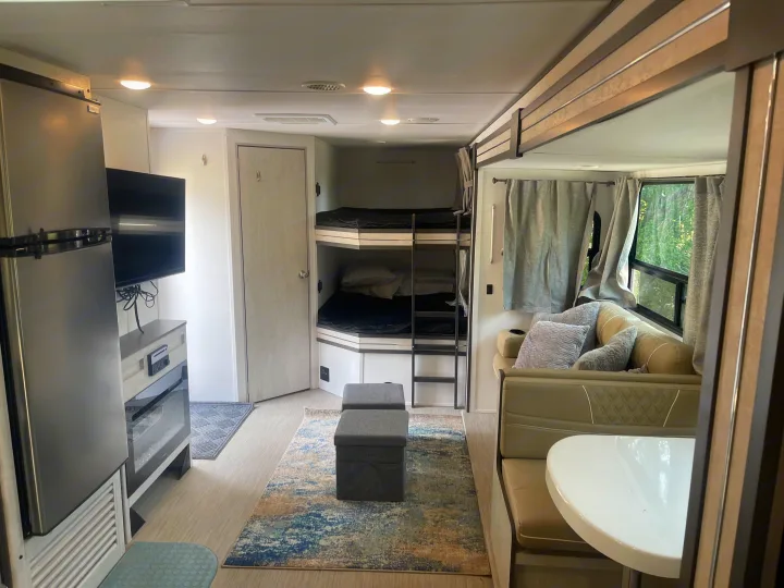 Inviting rv rental interior: visible bunk beds, dining area, fridge, and living space with a TV.. Travel Lite Evoke 2020
