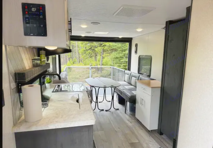 Cozy RV rental interior with kitchen, dining, and a rear patio deck opening to forest views. Perfect for camping adventures.. Sportsmen by KZ 250THLE 2022