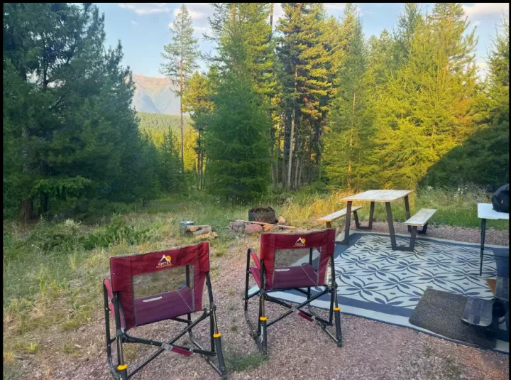 Enjoy this beautiful RV rental campsite! Features include a picnic table on a rug, chairs, fire pit, and mountain views amidst lush trees.. Sportsmen by KZ 250THLE 2022