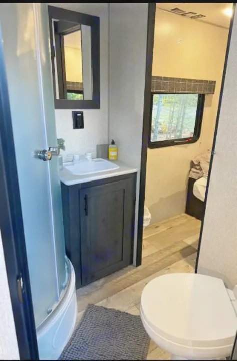RV rental bathroom features a compact shower, modern vanity, and toilet. View of trees outside window provides natural light.. Sportsmen by KZ 250THLE 2022