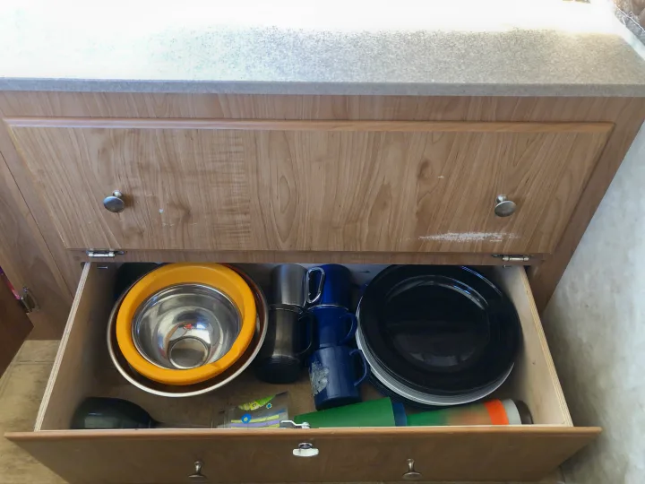Organized kitchen items in an **rv rental** drawer: metal bowls, enamel mugs, and plates ready for camping trips.. Fleetwood santa fe 2008