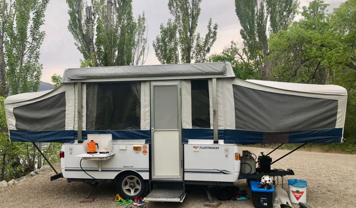 Pop-up RV rental set up at a peaceful campsite, featuring an outdoor kitchen and equipment.. Fleetwood santa fe 2008