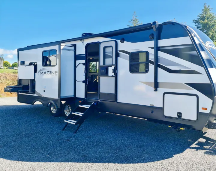 This white & black Grand Design Imagine travel trailer RV rental is ready! Features outdoor kitchen and deployed steps.. Grand Design Imagine 2023