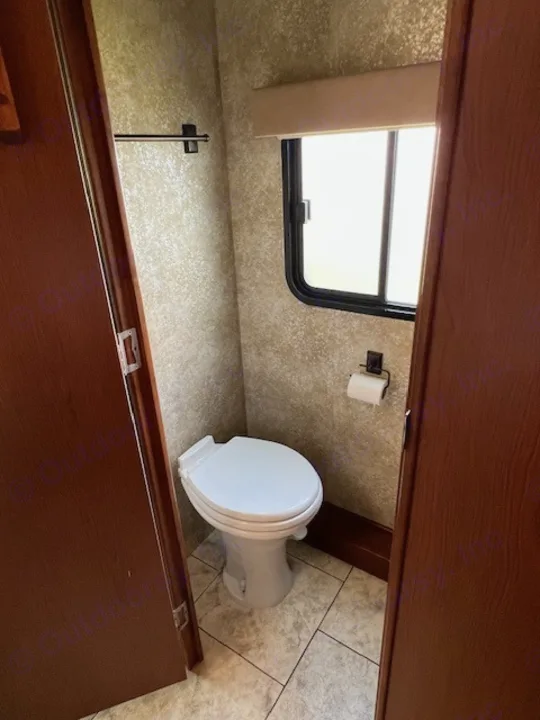 Compact RV rental bathroom featuring a toilet, window, tiled floor, and towel bar.. Allegro Tiffin Allegro Open Road 2012