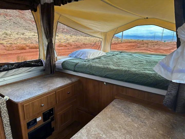 Inside an RV rental pop-up camper: a comfy bed with desert views.. Forest River Rockwood Premier 2017
