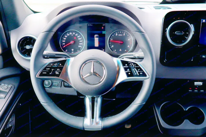Mercedes-Benz RV rental driver's cabin: modern steering wheel, digital instrument cluster, and dashboard controls are clearly visible.. Mercedes-Benz Sprinter 2025