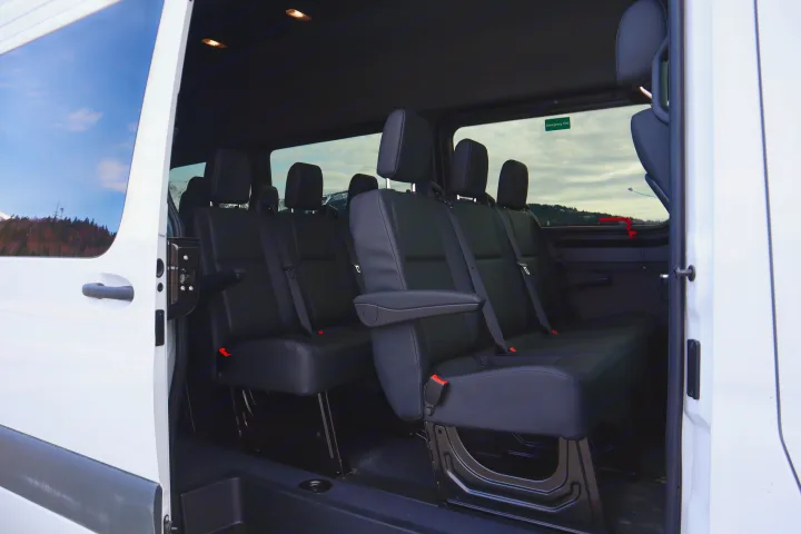 Spacious black passenger seating inside an RV rental van, perfect for group travel with views of mountains.. Mercedes-Benz Sprinter 2025