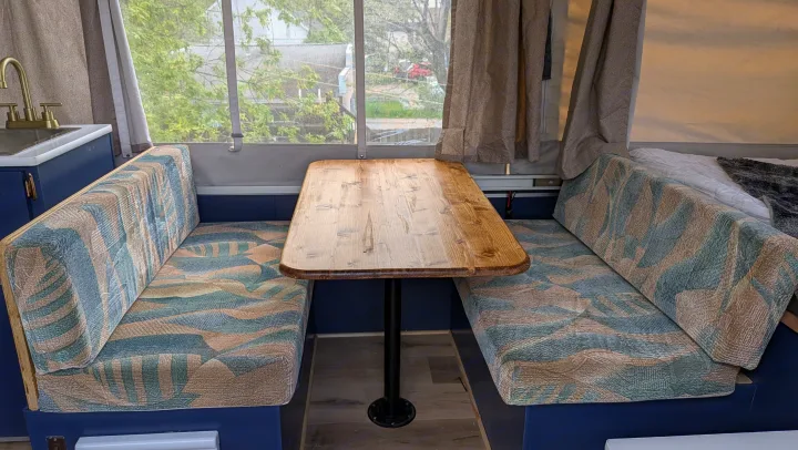 Inside an RV rental: a comfortable dinette with patterned cushions, a wooden table, and a functional sink area.. Coachmen Clipper 2008