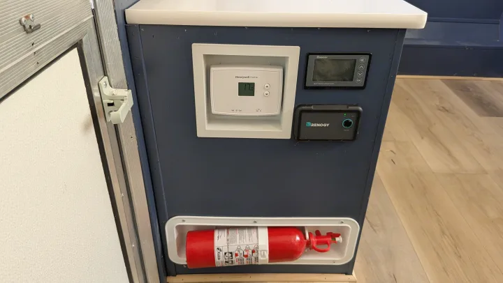 RV rental interior showing a Honeywell thermostat, Renogy battery monitor, and a visible fire extinguisher for safety and comfort.. Coachmen Clipper 2008