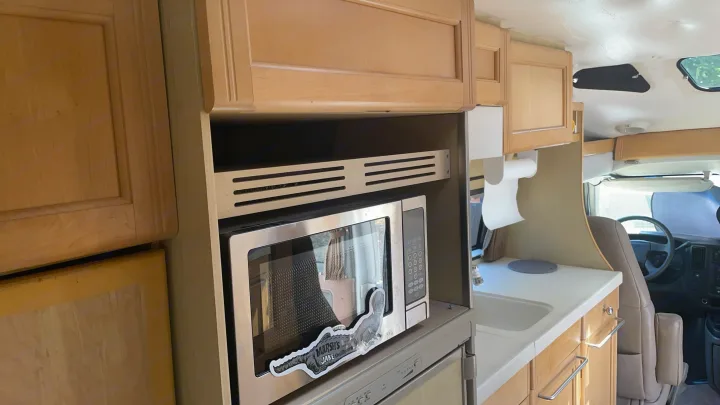 Cozy RV rental kitchenette with microwave, sink, paper towels, and light wood cabinets, ready for your next adventure.. Roadtrek 210 - Popular 2005