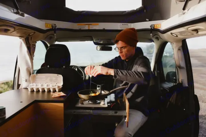 Enjoying mobile kitchen convenience in an RV rental! Man cooks eggs by the coast, embracing van life adventures.. Mercedes-Benz metris 2022