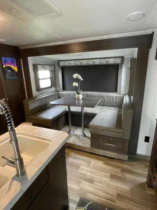 Spacious RV rental interior with a cozy dinette booth, table, and compact kitchen sink, ideal for travel.. Forest River Salem Cruise Lite 2020