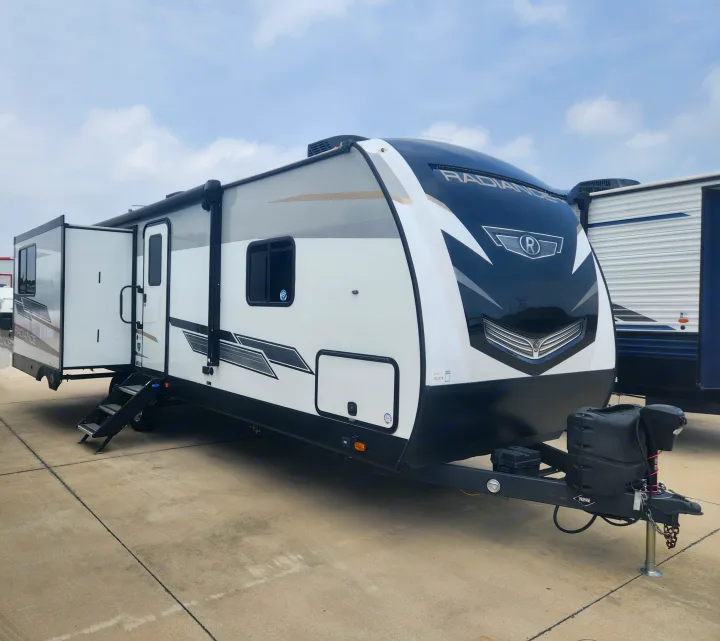 Sleek white, gray, and black travel trailer with an extended slide-out, parked outdoors. Great for RV rental.. Cruiser RV Radiance 2022