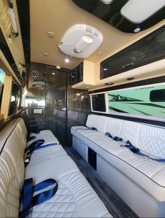 Spacious RV rental interior with cream-quilted benches, sleek dark wood accents, and ceiling AC unit.. Ultimate Toys Ultimate RV 2021