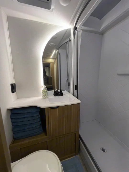 This clean RV rental bathroom showcases a light-up mirror, vanity, and a sleek shower with patterned walls.. Forest River 28VBXLX 2025