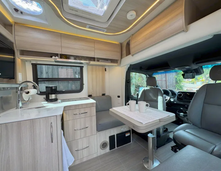 Modern RV rental interior: spacious kitchenette, cozy dining area & comfortable seating.. Leisure Travel Vans Unity 2022