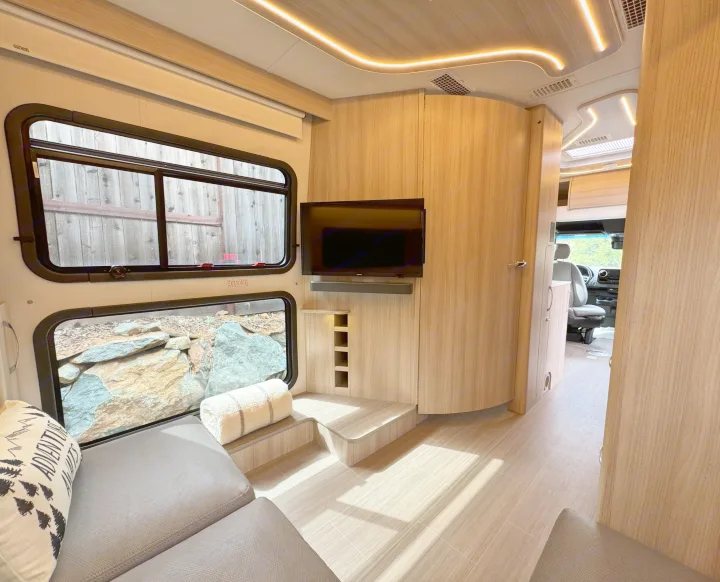Experience a luxurious RV rental! This modern interior boasts a comfy lounge, wide windows, TV, and elegant wood finishes with LED lighting.. Leisure Travel Vans Unity 2022
