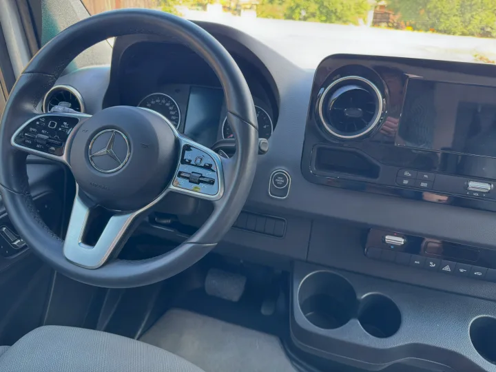 RV rental interior: modern Mercedes-Benz dashboard, steering wheel with controls, and practical cup holders.. Leisure Travel Vans Unity 2022