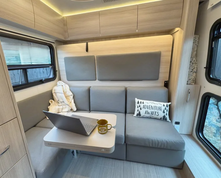 Cozy RV rental interior with a laptop on a table, perfect for work or relaxation during your next adventure.. Leisure Travel Vans Unity 2022