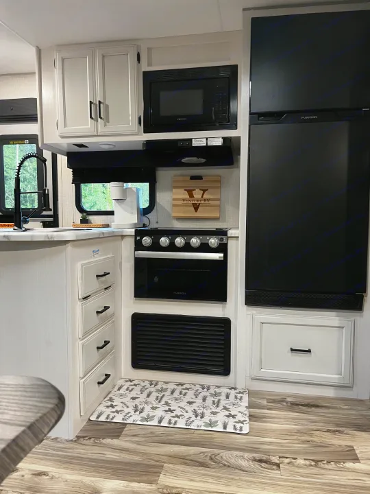 Compact and modern kitchen inside an RV rental, featuring Furrion appliances (fridge, oven, microwave), sink, and light cabinets.. Venture SPORTTREK 332VBH 2021