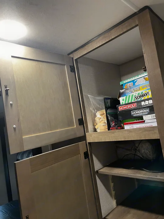 RV rental interior: Open shelves stocked with board games like Monopoly, Sorry!, Jenga, and other travel necessities.. Venture SPORTTREK 332VBH 2021