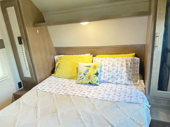 Cozy RV rental bedroom interior, featuring a comfortable bed with sunflower pillows and smart storage solutions.. Keystone RV Hideout 2020
