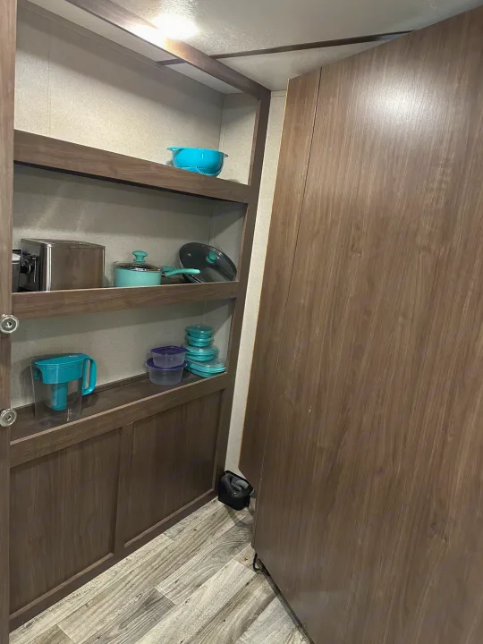 Functional RV rental kitchen storage: open shelves with a toaster, cookware, water pitcher, and food containers.. Keystone RV Hideout 2020