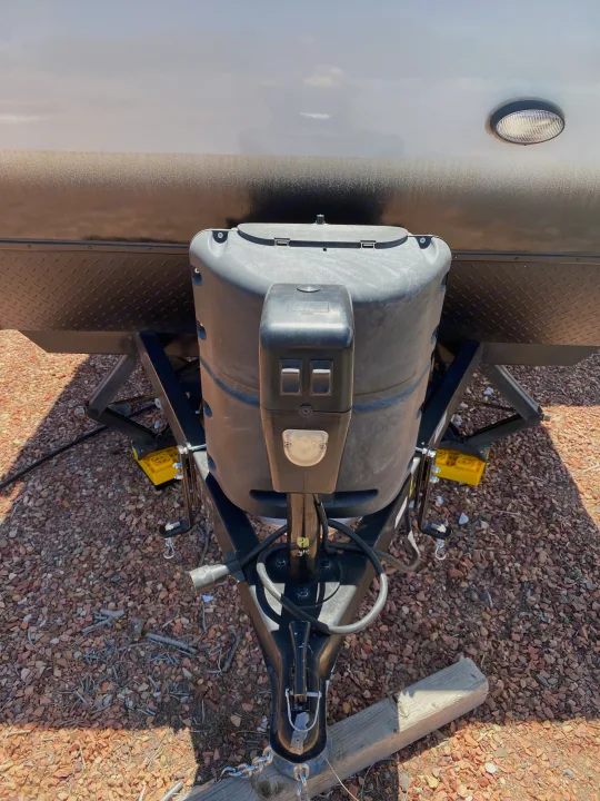 Front hitch of an RV rental, showing propane tank cover, electric tongue jack, coupler, and safety chains on gravel.. R-Pod Hood River Edition 2018