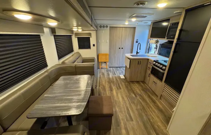 Spacious RV rental interior featuring a modern kitchen, dining booth, and comfortable lounge area. Perfect for travel.. Keystone RV Passport SL 2021