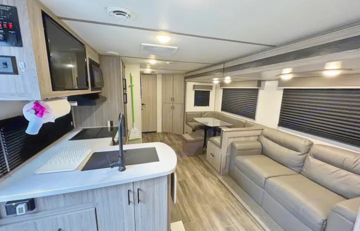 Explore this modern RV rental interior: a full kitchen, U-shaped dinette, and comfy sofa in a bright, spacious living area.. Keystone RV Passport SL 2021