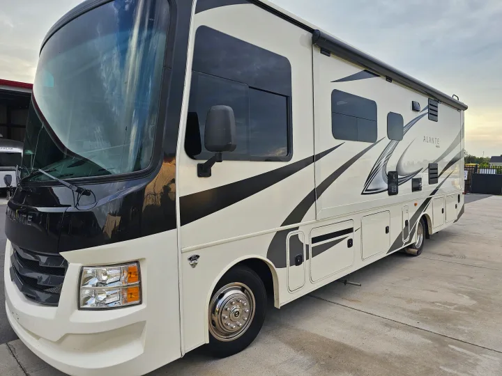 A cream and black Alante Jayco RV, ideal for an RV rental, is parked on a concrete lot under a cloudy sky.. Jayco Alante 2022