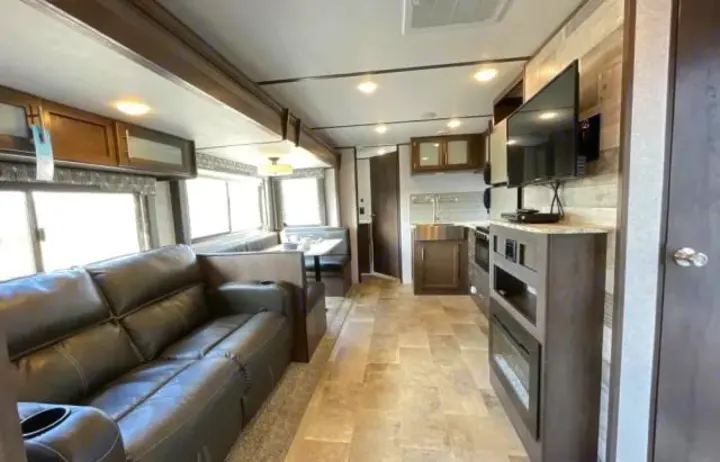 Spacious RV rental interior featuring a comfy sofa, dinette, full kitchen, and entertainment center, perfect for road trips.. Dutchmen Coleman Light 2020