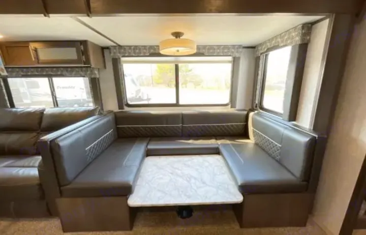 Spacious RV rental dinette with U-shaped seating, quilted cushions, and a table, perfect for meals and lounging inside the camper.. Dutchmen Coleman Light 2020