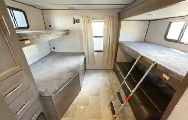 Spacious RV rental bunkhouse with four bunk beds, a ladder, sofa, and storage. Ideal for family trips.. Dutchmen Coleman Light 2020