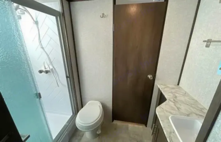 This RV rental boasts a well-equipped, compact bathroom with a glass shower, toilet, and vanity sink for your travels.. Dutchmen Coleman Light 2020