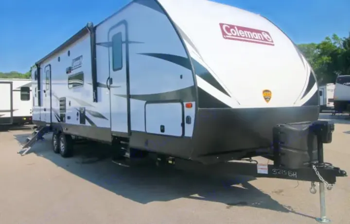 White Coleman travel trailer RV rental with awning extended and steps down, parked outdoors.. Dutchmen Coleman Light 2020