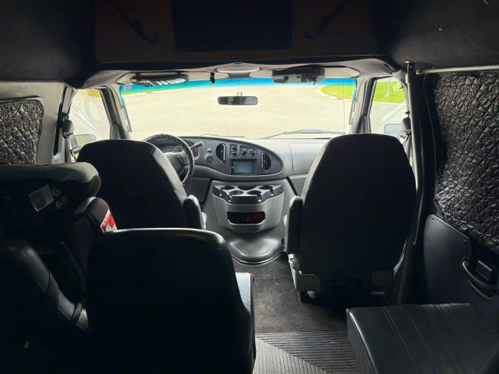 Inside a comfy rv rental conversion van: dashboard, front seats, and child safety seat visible.. Ford E350 Super Duty 1-ton Camper Van 2006