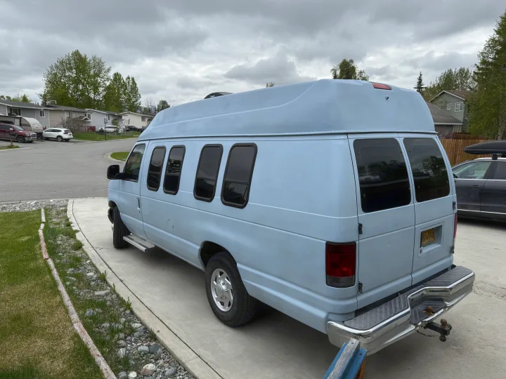 Light blue high-top conversion van, a great option for an RV rental, parked in a residential driveway.. Ford E350 Super Duty 1-ton Camper Van 2006