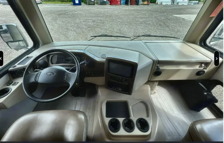 Inside an RV rental: driver's cockpit view with dashboard, Ford steering wheel, central display, and cup holders. Ready for travel.. Thor Windsport 2019