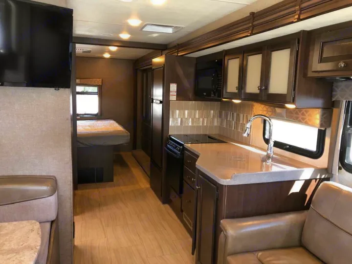 RV rental: Modern interior with kitchen, spacious living area, mounted TV, and bedroom.. Thor Windsport 2019