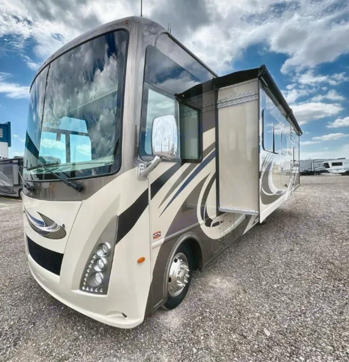 A sleek, modern Class A motorhome in beige and brown, featuring an extended slide-out. Explore your next RV rental adventure.. Thor Windsport 2019