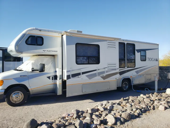 This Fleetwood Tioga motorhome RV rental, with its slide-out extended, is parked for outdoor adventure under a blue sky.. Fleetwood Tioga 31M 2007
