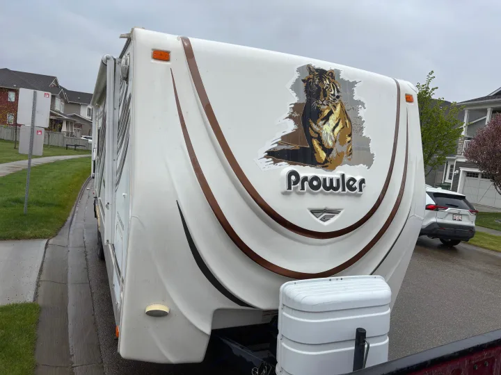 Front view of a white Prowler travel trailer, featuring a bold tiger graphic. Perfect for an RV rental adventure!. Fleetwood 230RKS 2009